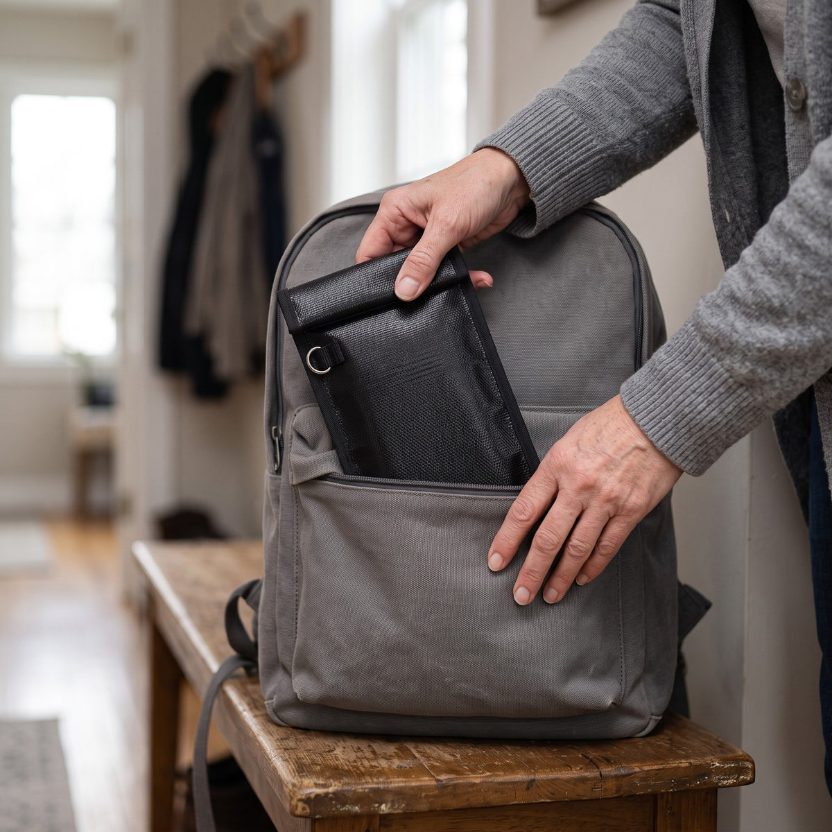 Zwei Hände stecken die NULLSIGNAL X1 in einen Rucksack im Flur